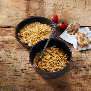 Trek'n Eat Pasta Creamy Mushrooms + Beef bereid in zwarte kommen op houten tafel met tomaten en brood