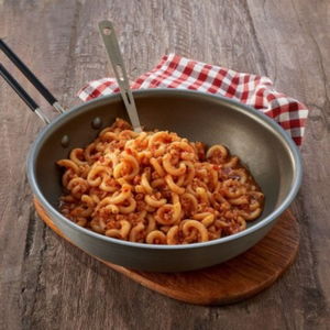 Trek'n Eat Pasta met vegetarische bolognesesaus bereid in een koekenpan op een houten ondergrond met rood-wit geruite doek