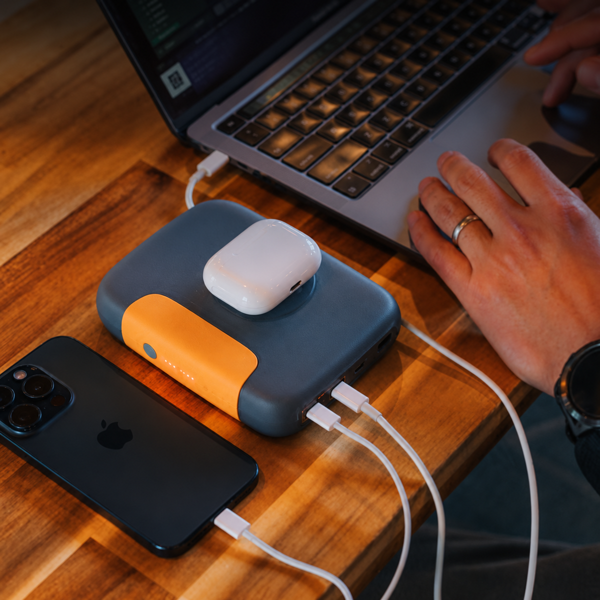BioLite Charge 100W powerbank in grijs en oranje die tegelijkertijd een smartphone, oordopjes en laptop oplaadt