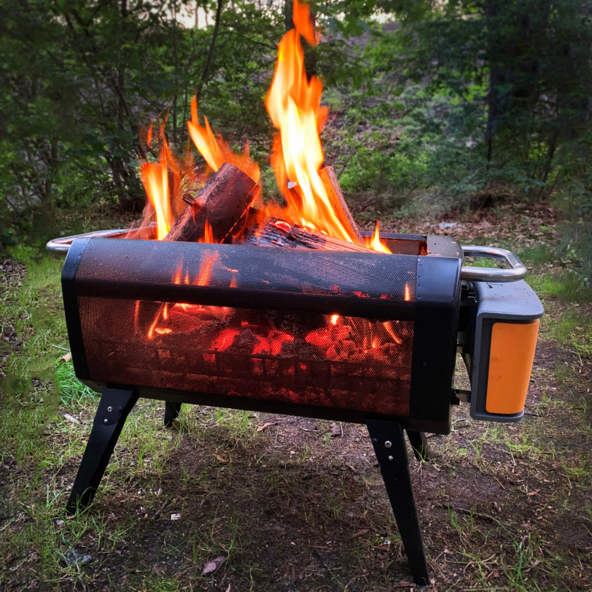 BioLite FirePit+ draagbare rookloze vuurkorf en barbecue met ventilator en oranje accenten brandend in de natuur