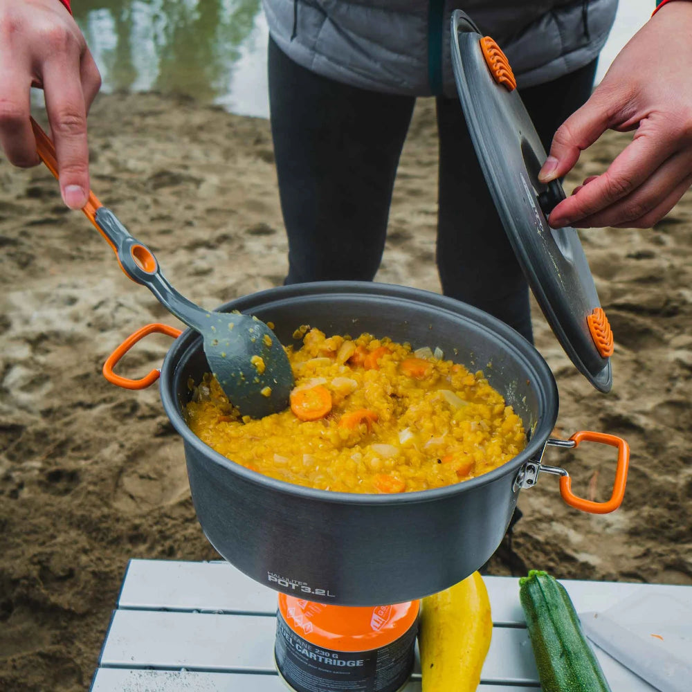 GSI Outdoors Halulite Pot 3.2L grijze aluminium kookpan met oranje handgrepen, deksel en opscheplepel tijdens kamperen
