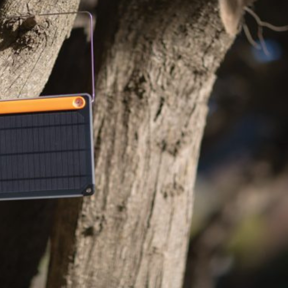 Goal Zero Nomad draagbaar zonnepaneel met oranje accenten dat hangt aan een boom in de natuur