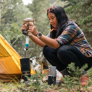 Hiker filtert water met de HydraPak 28mm kit bij een tent tijdens de hike