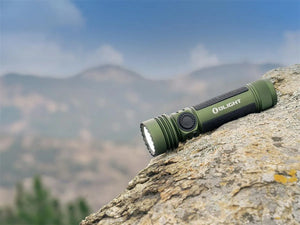 Olight Seeker 4 Pro OD Green olijfgroene oplaadbare LED zaklamp met ingeschakeld licht op een rots in een berglandschap