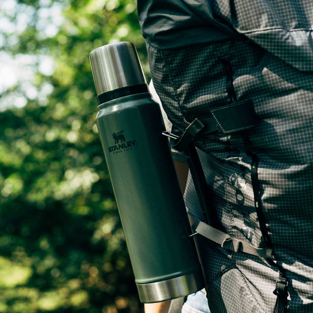 Stanley Classic Legendary rvs thermosfles in de kleur hammertone green bevestigd aan een rugzak in de natuur