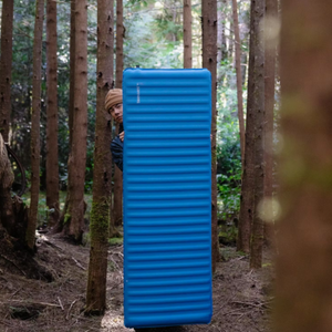 Therm-a-Rest Trail Pro MAX blauwe slaapmat rechtopstaand tussen bomen in een bos