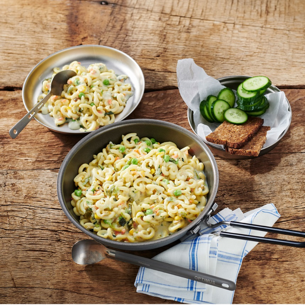 Trek'n Eat Pasta with Vegetables bereid in een pan met komkommer en knäckebröd op een houten ondergrond