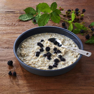 Trek n Eat Protein Porridge stazak tijdens een pauze in de natuur met een lepel en gevriesdroogde havermoutmaaltijd