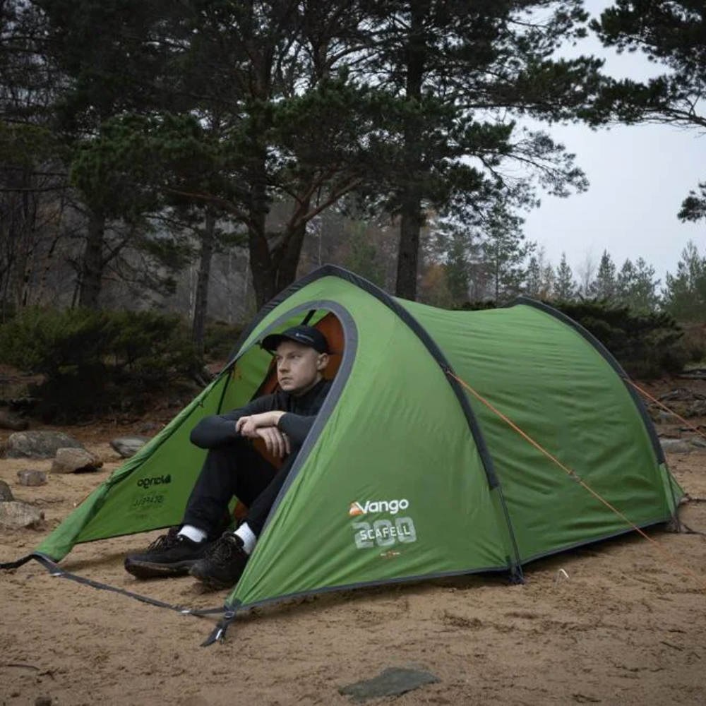 Vango Scafell 200 groene 2-persoons koepeltent opgezet in een bosrijke omgeving met iemand zittend in de opening  