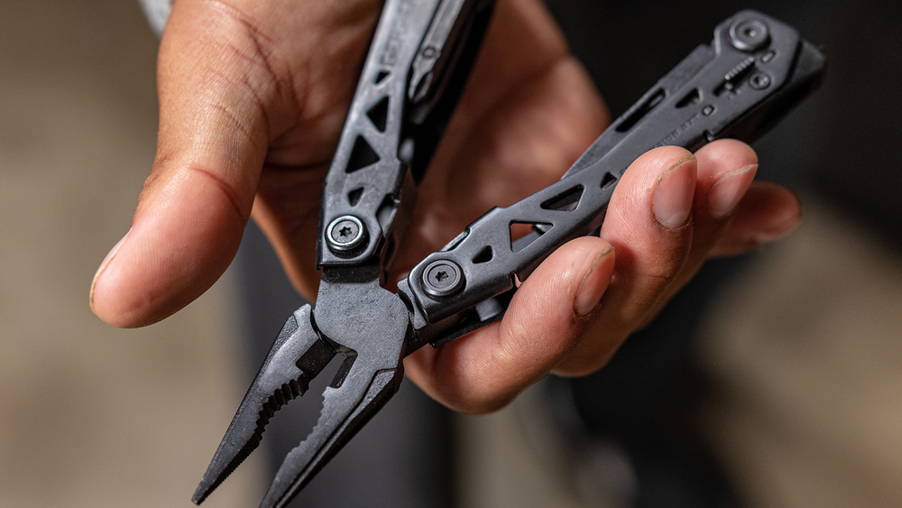 Een zwarte multitool in de hand tijdens het klussen of kamperen bij outdoor activiteiten